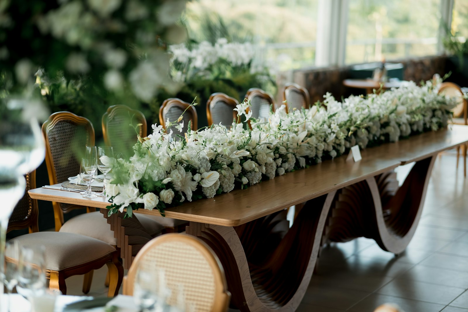 Mesa larga con un camino de flores blancas